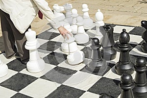 Detail of men playing gigantic chess outdoors on a sunny day.