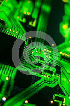 Detail of a microprocessor, resistors and capacitors soldered to a green glowing PCB
