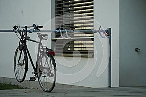 Detail of a visitors bicycle parking place in front of a residential building with a parked bike as an example.