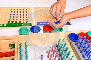 Detail of a montessori board division with the hand of a guide and teacher showing how to perform the operation
