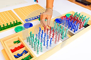Detail of a montessori board division with the hand of a guide and teacher showing how to perform the operation