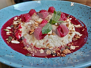Detail of muesli breakfast with raspberry jam, raspberries, mint, and seeds