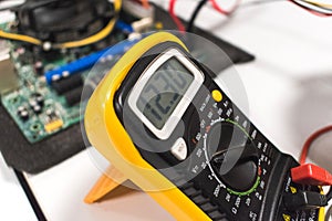 Detail of a multimeter with a computer motherboard in background