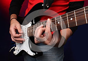 Detail of a musician playing a black electric guit