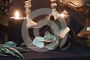 Detail of mysterious looking still life with handmade burning candles and stabilized dried leaves, craft art of wedding decoration