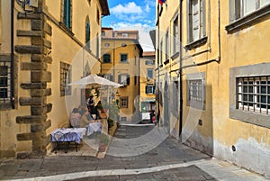 Detail of narrow street in old historic alley in the medieval City of Cortona with people on restaurant outdoor tables