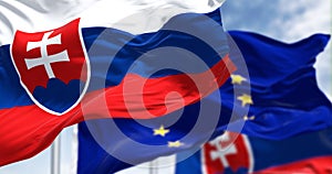 Detail státní vlajky Slovenska mávající ve větru s rozmazanou vlajkou evropské unie