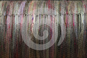 Detail of natural and colourful sheep wool fibres on a drum carding machine for spinning on a spinning wheel.