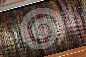 Detail of natural and colourful sheep wool fibres on a drum carding machine for spinning on a spinning wheel.