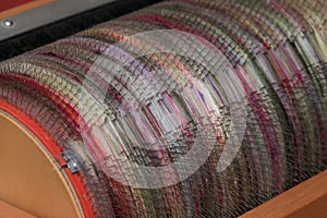 Detail of natural and colourful sheep wool fibres on a drum carding machine for spinning on a spinning wheel.