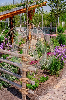 Detail of natural garden fence made of wooden posts and ropes with native plants and patio