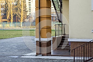 Detail of new kindergarten or school building corner with supporting column, staircase, metal fence and handrails on sunny