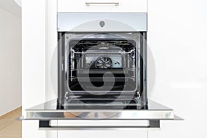 Detail of a new open oven with two baking trays inside. Interior of a modern white kitchen