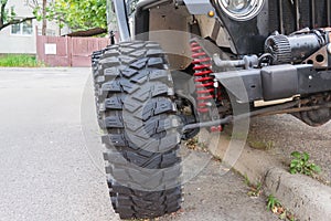 Detail of offroad vehicle showing big tire and red coil suspension