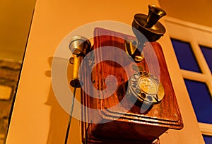 Detail of an old antique wooden frame analogue dial telephone with a separate microphone.