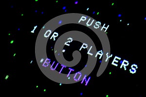 Detail on an old arcade video screen with text Push 1 or 2 players button