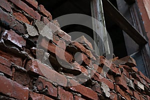 Detail of an old brick building. Wooden window frame without glass and dilapidated brickwork