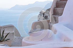 Detail of old church dome with blurred Greek building with stairs and seascape, Oia, Santorini, Greece