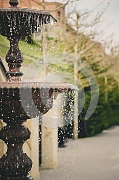 Detail of an old classic style fountain with flowing water. Outdoor garden fountain.