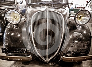 Detail of old french car with radiator grille and round light, vintage and retro background