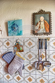 Detail of an old kitchen with potholders, ladles and a framed image of San Giovanni XXIII Angelo Giuseppe Roncalli