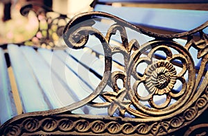 Detail of old park bench with ornaments, bokeh background