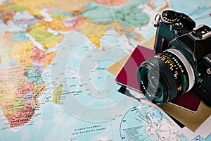 Detail of old photo camera and a passport on a world map. Adventure travel concept. Copy-space