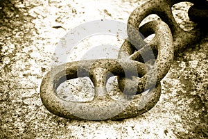 Detail of an old rusty metal chain anchored to a concrete block