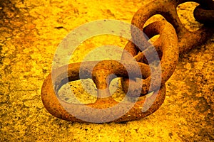 Detail of an old rusty metal chain anchored to a concrete block