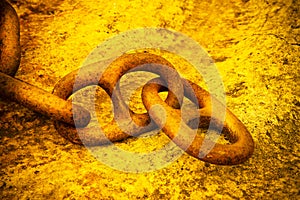 Detail of an old rusty metal chain anchored to a concrete block