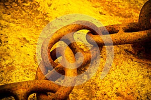 Detail of an old rusty metal chain anchored to a concrete block
