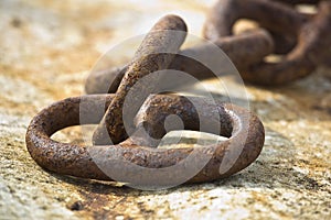 Detail of an old rusty metal chain anchored to a concrete block