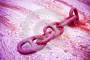 Detail of an old rusty metal chain anchored to a concrete block