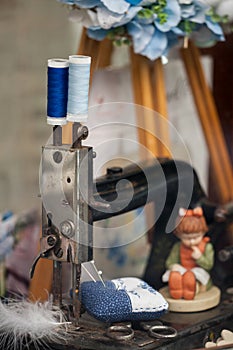 Detail of old sewing machine, scissors and vintage spools of thread. Handmade pincushion