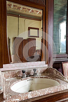 Detail old sink with mirror above in bedroom. Interior of an abandoned villa to be restored