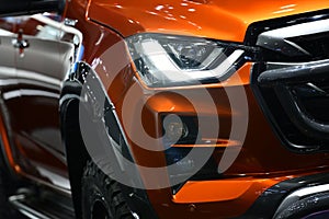 Detail on one of the LED headlights orange Pickup Truck on black background