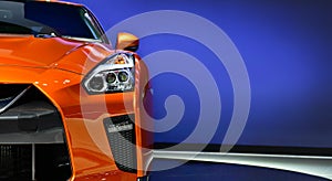 Detail of the one LED headlights orange sport car on blue background