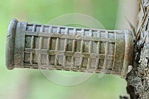 detail from one old gray plastic grip for the handlebars of a bicycle hanging on the wall