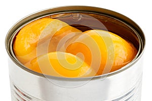 Detail of open can of peach halves in syrup on white ..