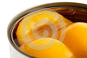 Detail of open can of peach halves in syrup on white.