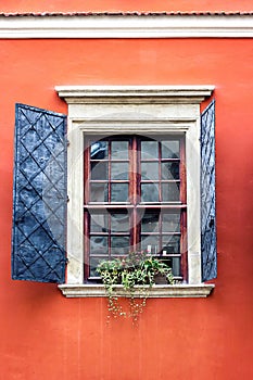 Detail of an open wooden iron vintage rustic windows on red cement old wall can be used for background. Brown black window shutter