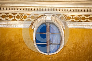 Detail of oval window on old yellow facade in a house in the old town of Caravaca photo