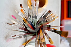 Detail of paint brushes and bright paint in an artistÃ¢â¬â¢s studio photo