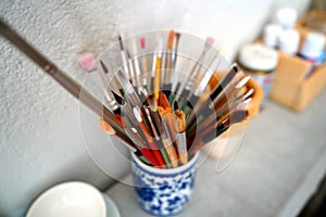 Detail of paint brushes and bright paint in an artistÃ¢â¬â¢s studio photo