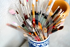 Detail of paint brushes and bright paint in an artistÃ¢â¬â¢s studio photo