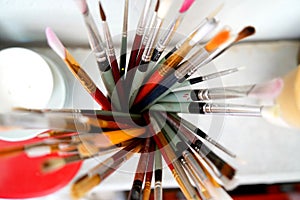 Detail of paint brushes and bright paint in an artistÃ¢â¬â¢s studio photo