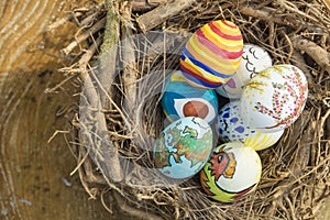 Detail of painted Easter eggs with different forms, cartoons and bright colors placed in a bird nest outdoors on a sunny day