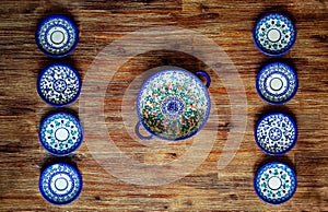 Detail of painted ornate pottery plates on wooden textured table in vintage style