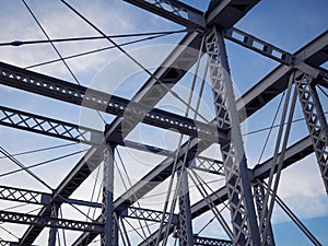 Detail of painted riveted bridge against blue sky.