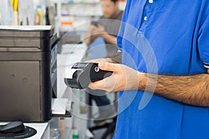 Detail of pharmacist hands holding a card reader at the counter